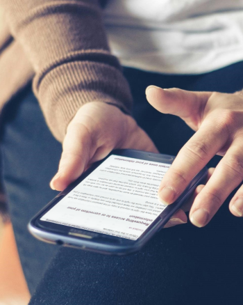 A white woman's hands hold a large smart phone. She is looking at the OPC website.