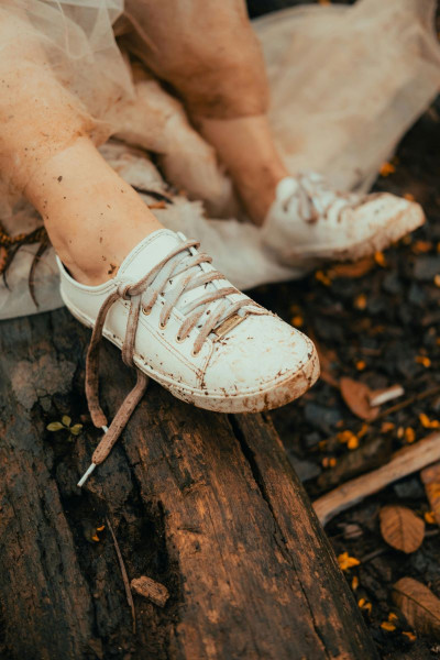 Dirty white shoes with unlaced shoelaces in a flooded, woody landscape