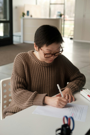 A person sitting at a desk, writing on a piece of paper.