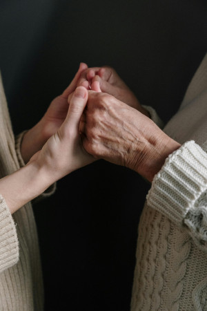 A young woman's hands hold and older person's hands