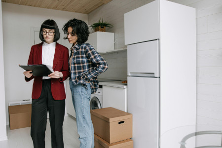 Two people look at paperwork in an empty apartment.