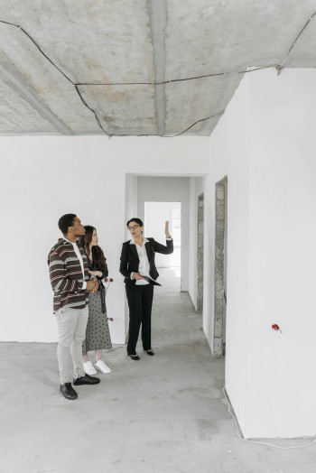 Two people viewing an empty apartment, with a property manager.